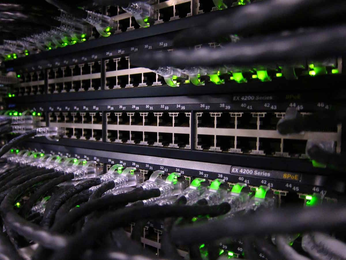 Close‑up of a network switch rack with Ethernet cables connected to active PoE ports.